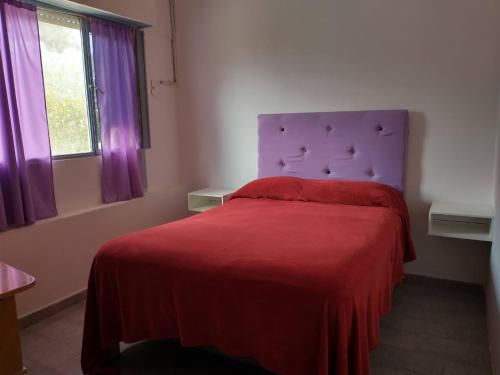 a bedroom with a red bed with a purple headboard at Lo de Nelly 1 in Puerto Madryn