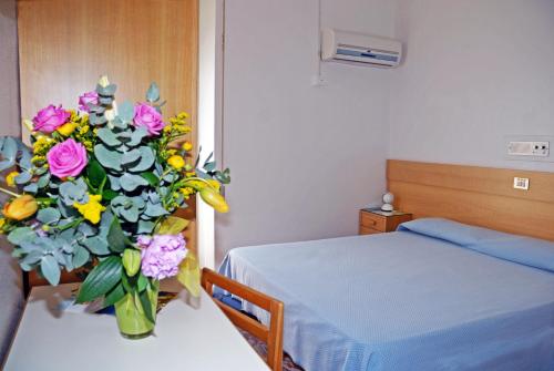a vase of flowers in a room with a bed at Albergo La Sirenella in Sperlonga