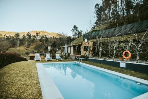 a swimming pool with two chairs and a house at Casa do Rio, 4890 in Basto