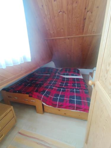 a small bed in a room with a wooden ceiling at Drevenica u Holtana in Oščadnica
