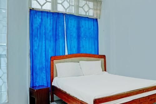 a bed in a room with a blue curtain at Hotel O Kost Axcel in Banjarmasin