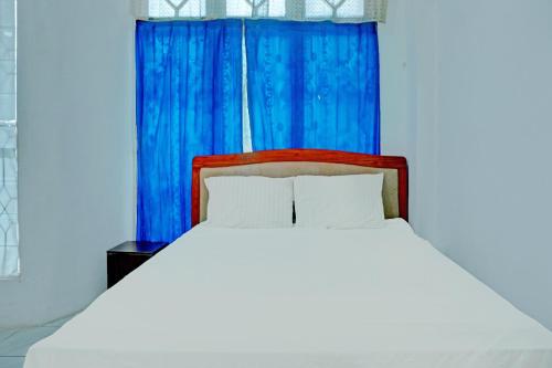 a bedroom with a bed with a blue curtain at Hotel O Kost Axcel in Banjarmasin