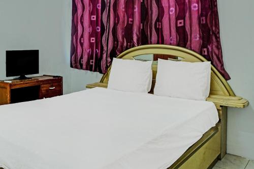 a bedroom with a bed and a television at Hotel O Kost Axcel in Banjarmasin
