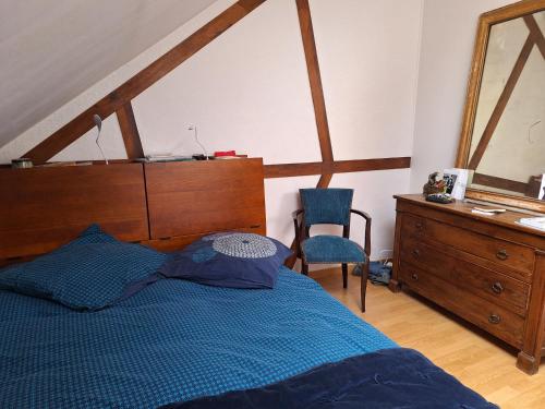 - une chambre avec un lit bleu et une commode dans l'établissement Les toits de Mantes, à Mantes-la-Jolie