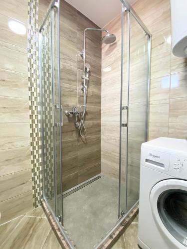 a shower in a bathroom with a washing machine at Zemunske kapije 2 Prizrenska in Novi Grad