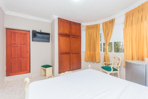 a bedroom with a white bed and orange curtains at Hotel Baluarte Cartagena Boutique in Cartagena de Indias