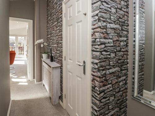 a door leading into a hallway with a stone wall at Gressingham View Lodge in Carnforth