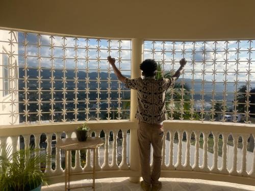 a man standing in front of a window with his arms up at Skyline Suites Villa and Spa in Montego Bay