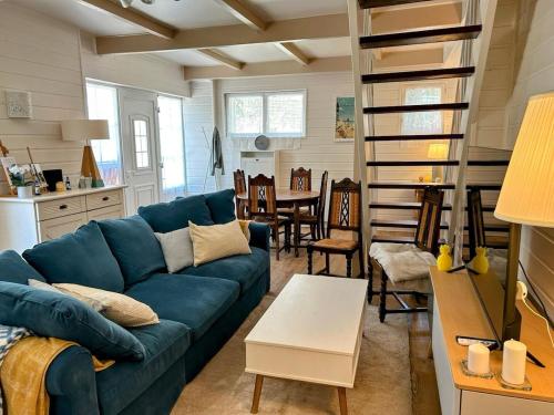 - un salon avec un canapé bleu et un escalier en colimaçon dans l'établissement Maison de vacances cosy à 5mn de la plage, à Merville-Franceville-Plage