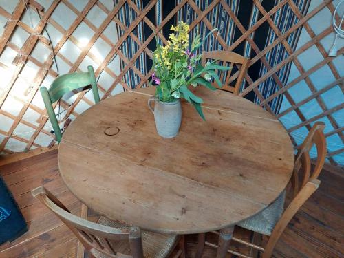 a wooden table with a vase of flowers on it at La yourte au cœur de la Normandie in Boudeville