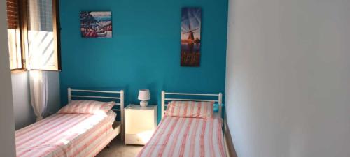 Dos camas en una habitación con una pared azul. en Villino Nausika fronte mare - B, en Torre Lapillo