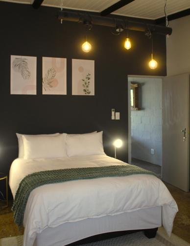 a bedroom with a large bed with white sheets at Lategansrus at Helpmekaar Farm in Wellington