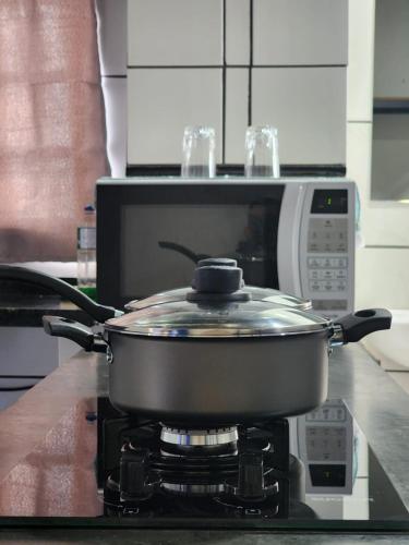 a pot on a stove in front of a microwave at Kitnet mobiliada em Lins in Lins