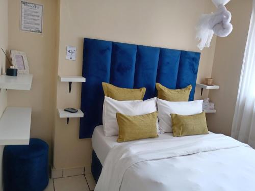 a bed with a blue headboard in a room at Olivia Pines Guesthouse 4 Bedroom Self Catering House in Krugersdorp