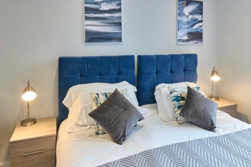 a bed with a blue headboard and two pillows at Host & Stay - Crosby Gardens Apartment in Crosby