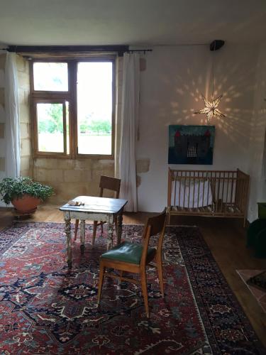 - un salon avec une table et des chaises sur un tapis dans l'établissement Grande chambre renaissance, à La Celle-sous-Gouzon