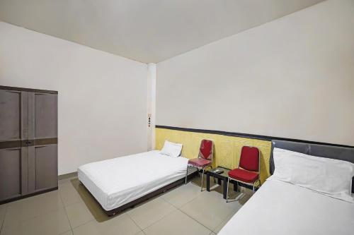 a bedroom with two beds and two red chairs at Hotel O Penginapan Metro Parepare in Parepare