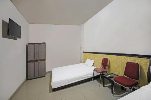 a small room with a bed and two chairs at Hotel O Penginapan Metro Parepare in Parepare
