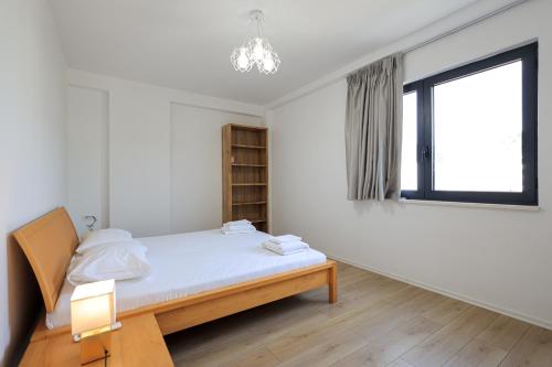 a white bedroom with a bed and a window at SanPietro Premium Villas in Draçi