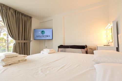 a bedroom with a white bed with a tv on the wall at SanPietro Premium Villas in Draçi