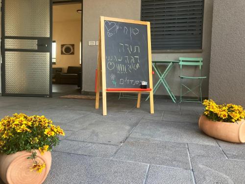 a chalkboard with writing on it next to two plants at בסנדלים: חאן בוטיק בגולן in Ma'ale Gamla