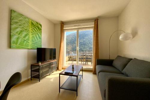 a living room with a couch and a television at Les Naïades C14 - 2 bedrooms for 6 people ! in Avène