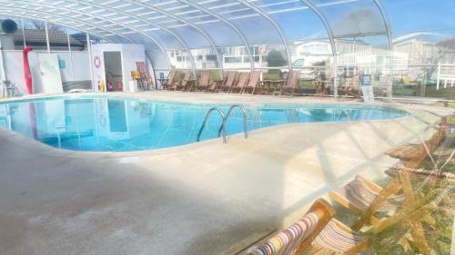 a large swimming pool with chairs and a building at Excellent caravan 4 birth sleeps 6 Tranquil site in East Mersea