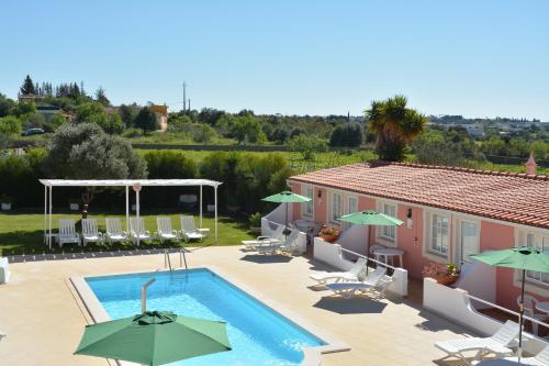 a swimming pool with chairs and umbrellas next to a building at SOLAR DOS AVÓS in Guia