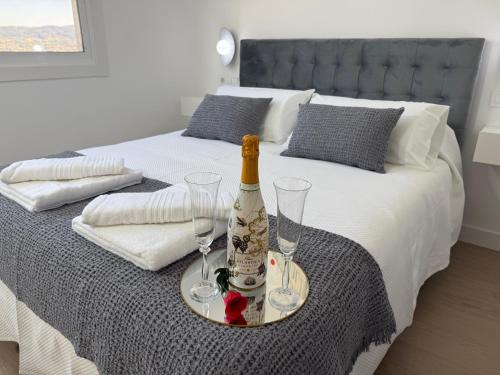 a bed with a bottle of wine and two glasses at La Casa del Horreo in Combarro
