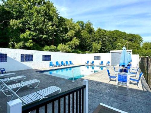 a swimming pool with chairs and umbrellas at The Village at Paugus Bay Condo! in Laconia