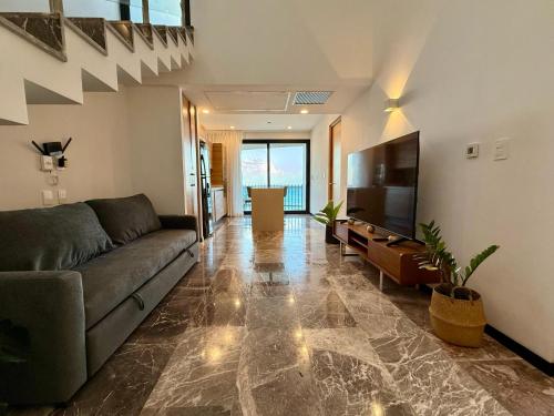a living room with a couch and a flat screen tv at It Beach Condo in Playa del Carmen
