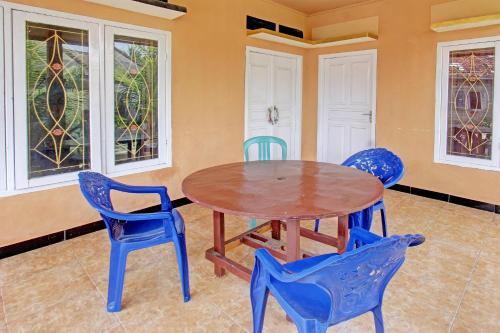 a table and chairs in a room with windows at Hotel O Zahira Homestay Near Ekas Surf School and Service in Ekas