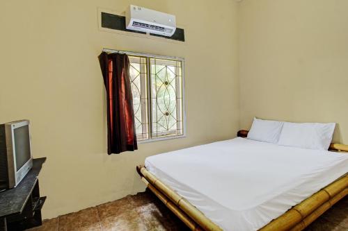 a bedroom with a bed and a window at Hotel O Zahira Homestay Near Ekas Surf School and Service in Ekas