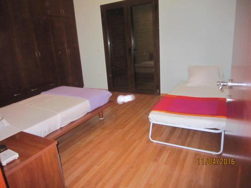 a bedroom with two beds and a wooden floor at Dimitris Villa in Aígio