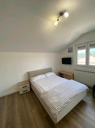 a white bedroom with a bed and a tv at Family Apartments Stefan in Budva