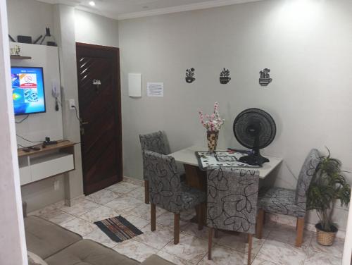 a dining room with a table and chairs and a television at Apto Boqueirão praia gde in Praia Grande