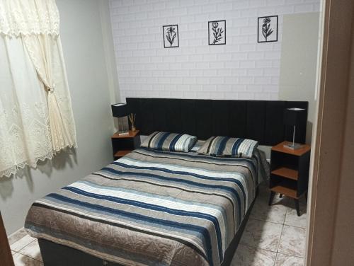 a bedroom with a bed with a striped blanket and two lamps at Apto Boqueirão praia gde in Praia Grande