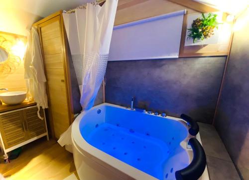 La salle de bains est pourvue d'une baignoire bleue. dans l'établissement La cabane balnéo vue mer, à Bazenville
