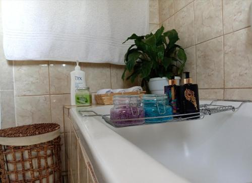 a bathroom counter with a shelf on the side of a bath tub at Olivia Pines Guesthouse 4 Bedroom Self Catering House in Krugersdorp