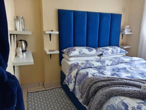 a bed with a blue headboard in a room at Olivia Pines Guesthouse 4 Bedroom Self Catering House in Krugersdorp