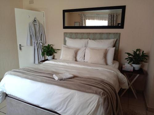 a bedroom with a large white bed with a mirror at Olivia Pines Guesthouse 4 Bedroom Self Catering House in Krugersdorp