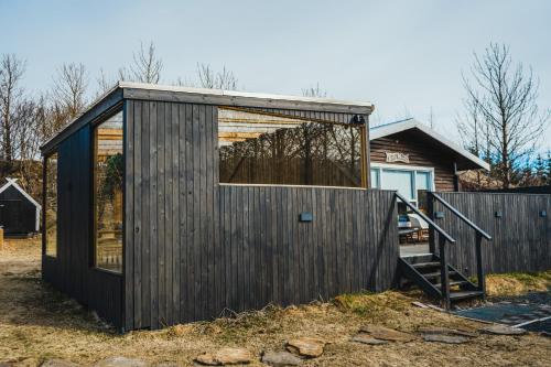 a wooden house with a large glass window at Eyja Mork - Aurora Igloo with shared Hot Tub, BBQ and kitchen - B2 in Stora Mork