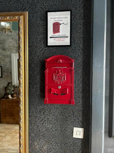 a red suitcase on a wall next to a mirror at Hostal imperio in Tomelloso