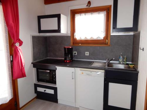 a small kitchen with a sink and a microwave at Chalet des FURETS in Xonrupt-Longemer