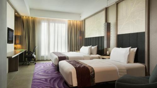 a hotel room with two beds and a chair at Holiday Inn Bandung Pasteur by IHG in Bandung