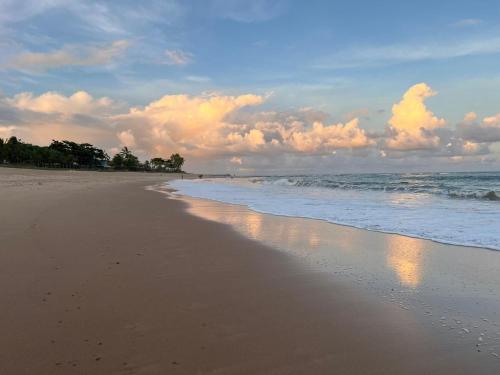 a beach with a cloudy sky and the ocean at Bioflora Itacimirim Novo village 44 in Camacari