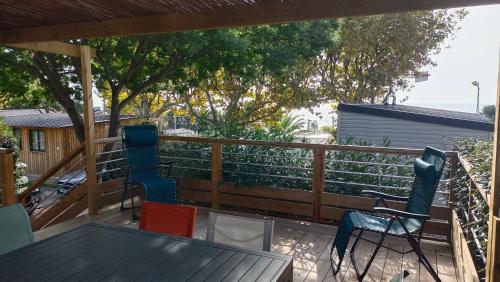 a deck with chairs and a table and a fence at Mobilhome neuf à Camping Domaine l'Ile d'Or à Saint Raphaël in Saint-Raphaël