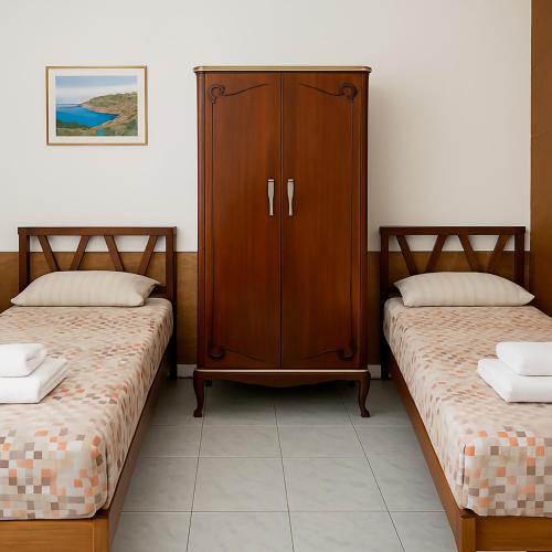 a bedroom with two beds and a cabinet at Valletta Door in Il-Furjana