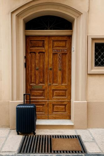 a suitcase sitting in front of a wooden door at Valletta Door in Il-Furjana