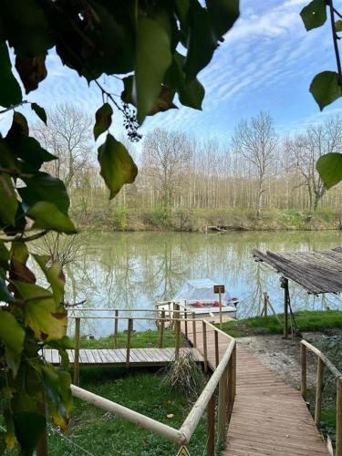 a wooden walkway next to a river with a boat at Domaine Kaet in Ratenelle